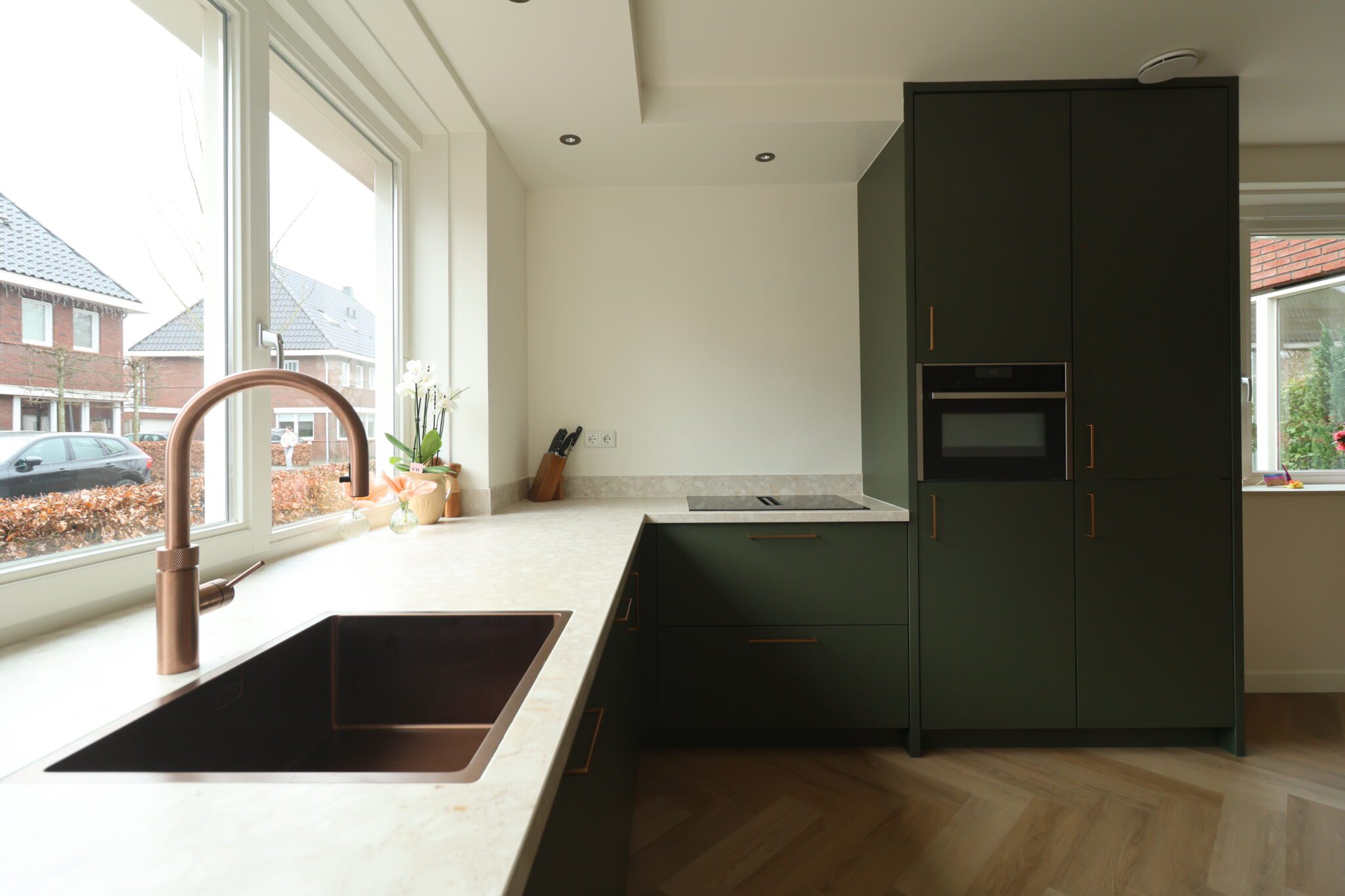 maatwerk hoekkeuken met geïntegreerde apparatuur en doorlopend werkblad langs het raam